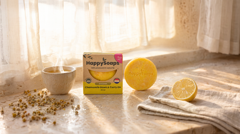 Shampoo Bar Chamomile Down & Carry On på en fönsterbräda med kamomillte, kamomillblommor och citron